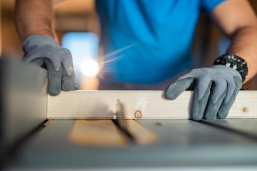 Close-up of males hands using circular saw at construction site